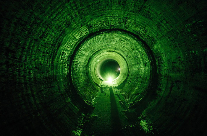 a long, dark, green-lit tunnel of the inside of a sewer line