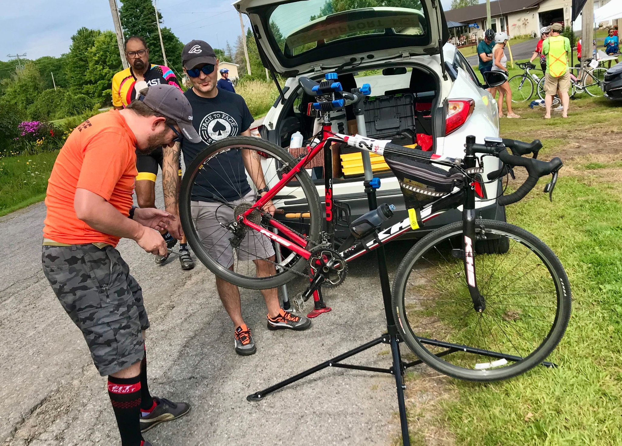 Photo of a support volunteer fixing the rear wheel of a road bike, held up on a tripod repair stand 
