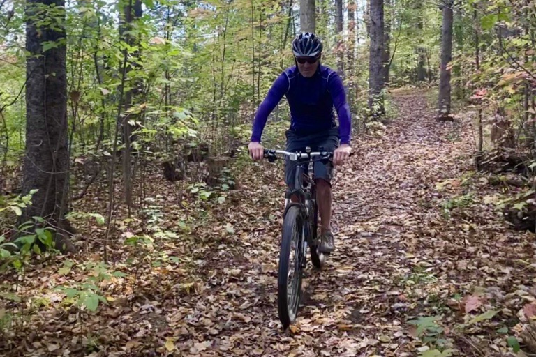 Cyclist in forest riding down a leafy path