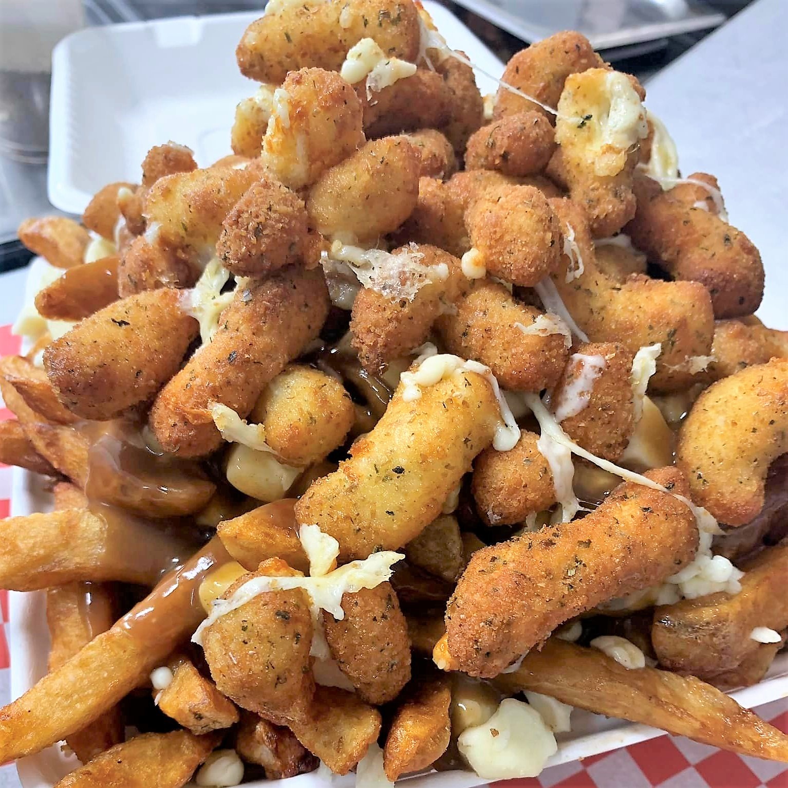 A mountain of deep fried cheese curds on top of poutine